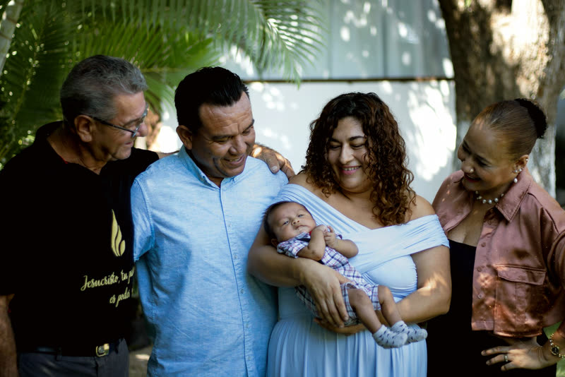 A family gathered outdoors around a new baby