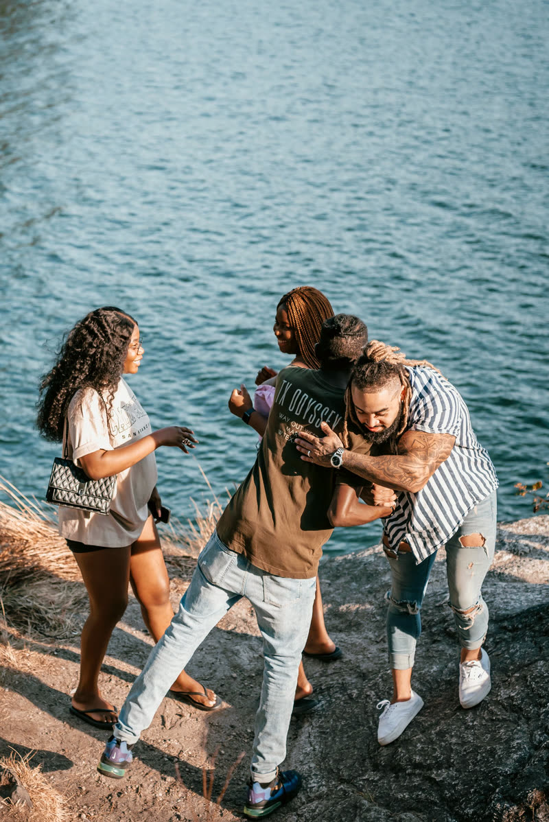 Friends piling into a group hug outdoors as they arrive to celebrate together