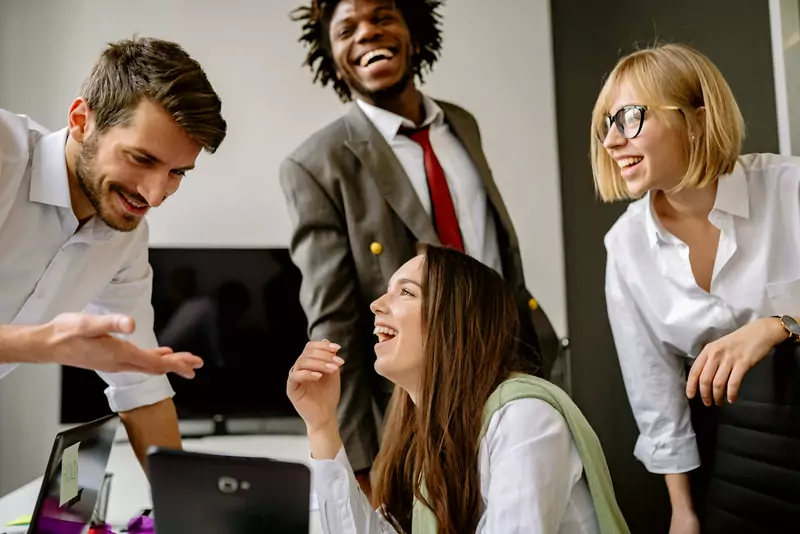 Colleagues gathered around a desk, laughing together at a send-off