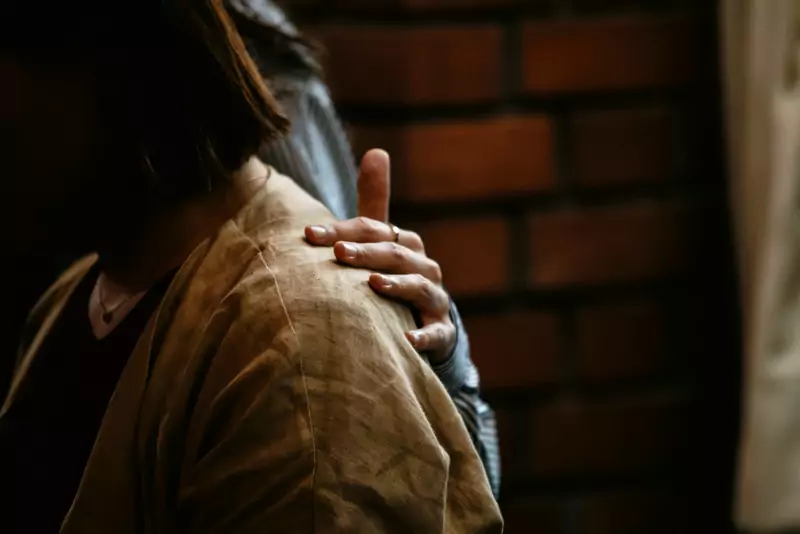 A reassuring hand resting on a colleague’s shoulder in a quiet moment of support