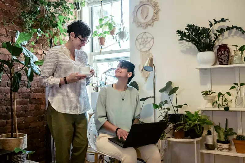 Two teammates sharing a light moment over coffee in a cozy workspace