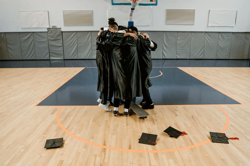 Graduates in gowns collapsing into a shared group hug