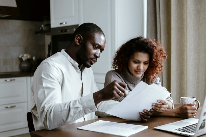 Two people sorting out bills together at the kitchen table