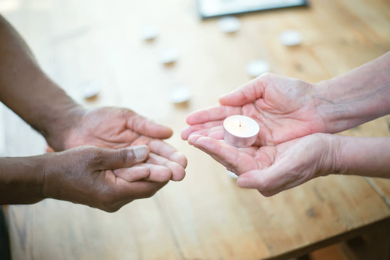Two hands passing a lit candle