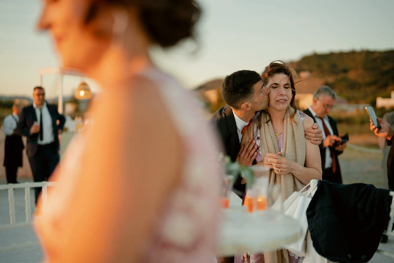 Wedding guests embracing at an outdoor reception in warm evening light